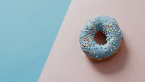 video of donut with icing on blue and pink background