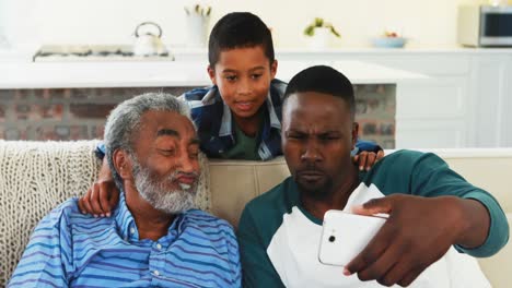 family taking selfie from mobile phone in living room
