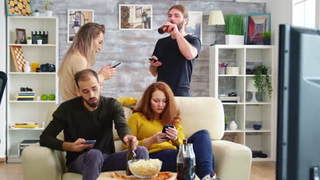 Young-man-taking-a-sip-of-beer-while-using-his-smartphone