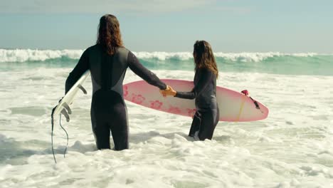 couple with surfboard holding hands on the sea 4k