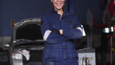 retrato de una mecánica con los brazos cruzados sonriendo en una estación de servicio de automóviles