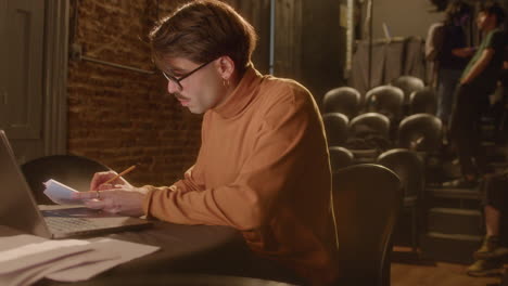 playwright using laptop and making notes on theater stage
