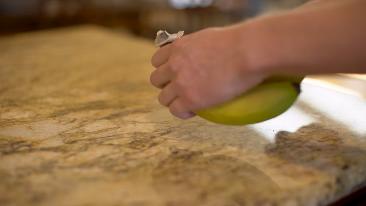 video fijo de una persona agarrando un plátano del mostrador de la cocina