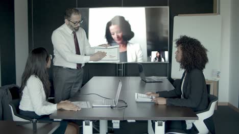 gerente barbudo de mediana edad que muestra gráficos y explica datos