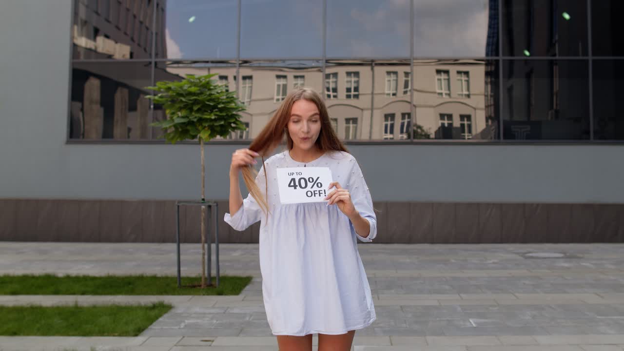 행복한 소녀는 할인 퍼센트 광고 문구를 보여주고, 기으로 소리치고, 쇼핑을 즐기고 있습니다.