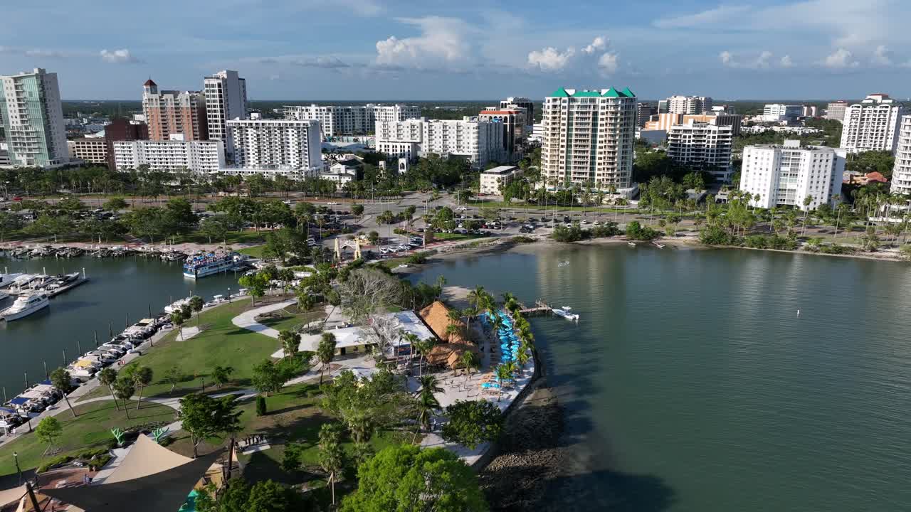 Sarasota Bayfront and skyline buildings of American town at sunny day. Aerial flyover shot. Marina with parking expensive yachts in Florida. Sunset time.