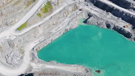 aerial footage of a turquoise lake in a quarry, showcasing vibrant colors and industrial surroundings under bright daylight
