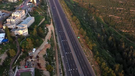 aerial view of an empty highway bordering a lush forest