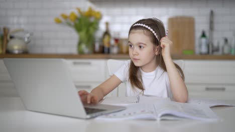 chica haciendo la tarea en línea en la cocina