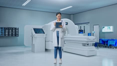 full body of asian woman doctor with stethoscope taking note on a tablet while standing with mri machine in the hospital