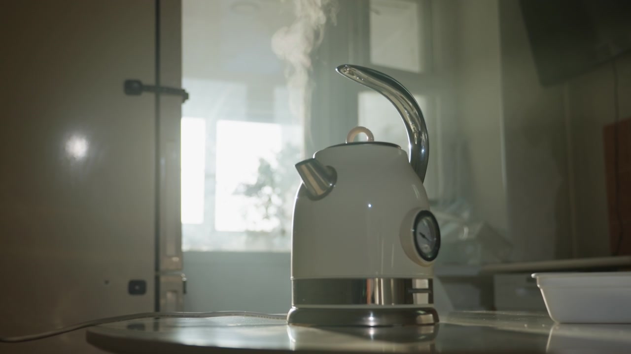 Bollitore fumante sul fornello alla luce del sole mattutino, bollitore retrò in metallo bianco con indicatore, vapore che sale attraverso la finestra, ciotola di ceramica sul bancone, bagliore cinematografico dell'obiettivo, rituale caldo e accogliente di slow living, delicato