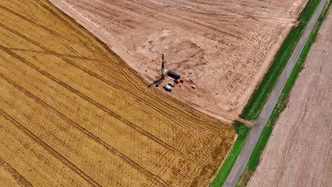 approaching the little site producing oil in the field. ripe wheat plantation near the industry. top view.