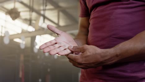 Biracial-sportsman-using-talc-on-hands-at-gym-in-slow-motion