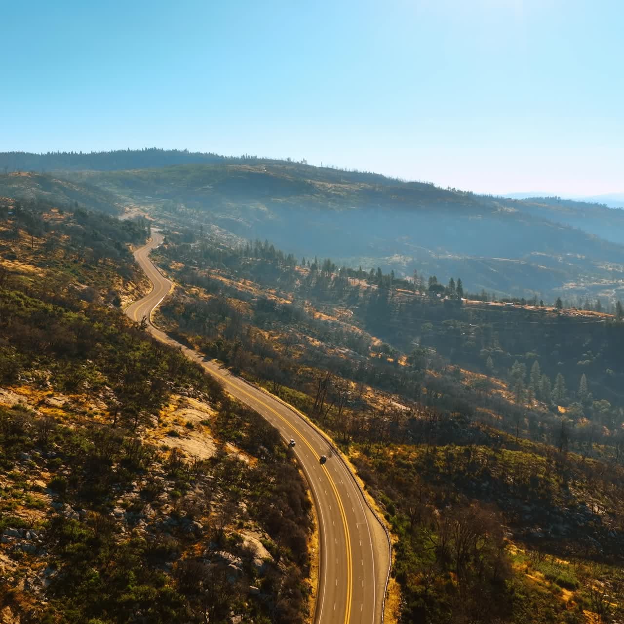 Flight over the highway in the mountains of Sierra National Forest, USA. Beautiful sunny scenery from top view
