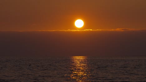 sol en el cielo durante la puesta de sol con vista al mar iluminada con hora dorada