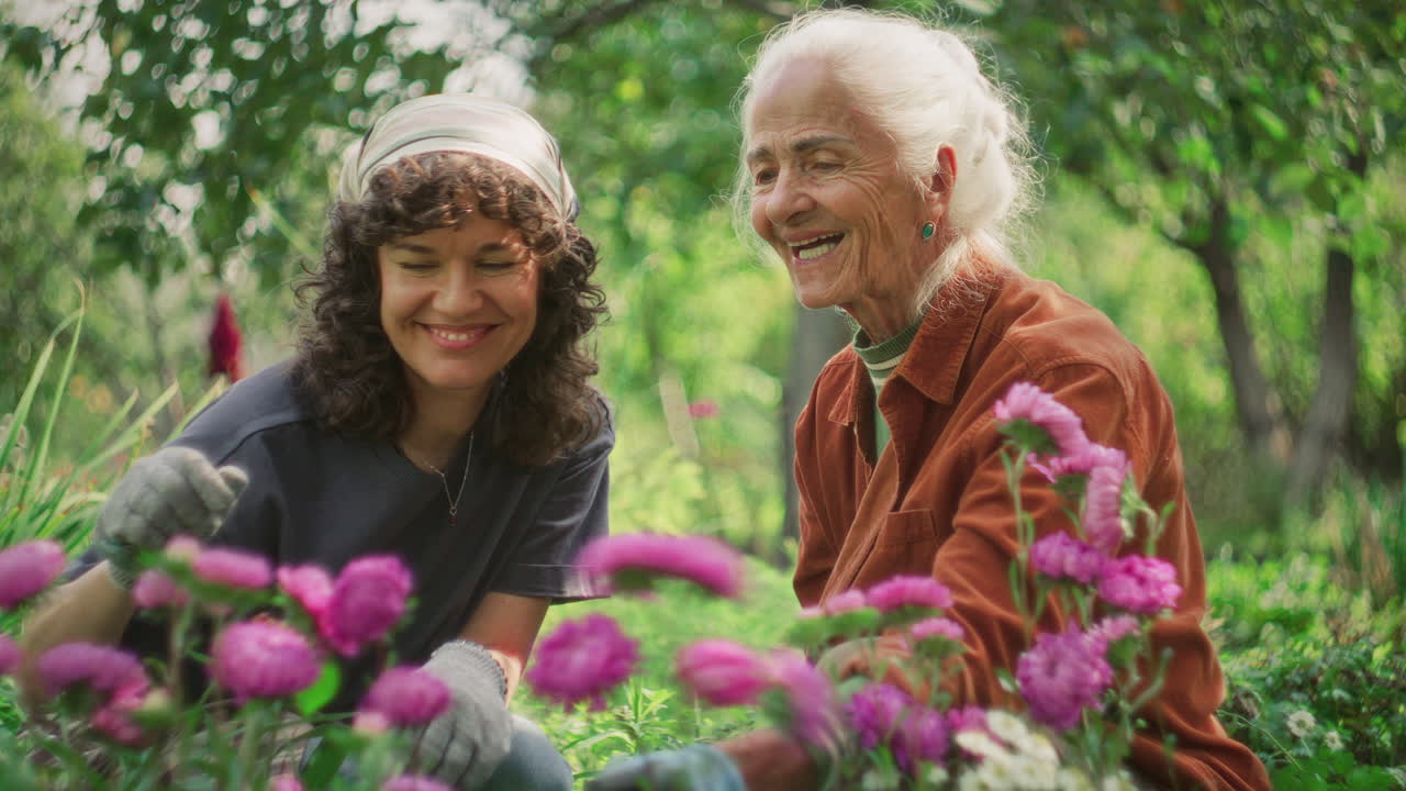 Smiling Senior and Young Women Tending Flowers Together in Garden