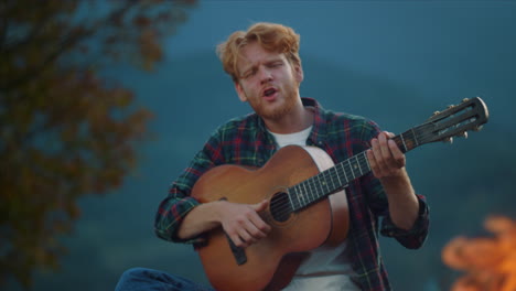 closeup musician enjoy evening in mountains. hipster guy play guitar on nature.