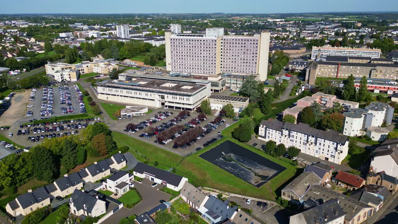 Laval hospital center, building, parking lots and surrounding cityscape, Mayenne, France. Aerial drone backward