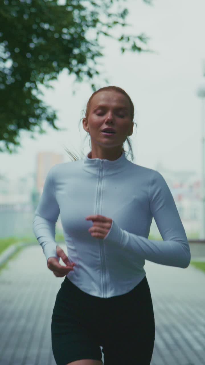 Una runner concentrata in movimento, immortalata in un sereno parco urbano, che mostra determinazione ed entusiasmo per il fitness attraverso un'intensa sessione di jogging all'aperto.