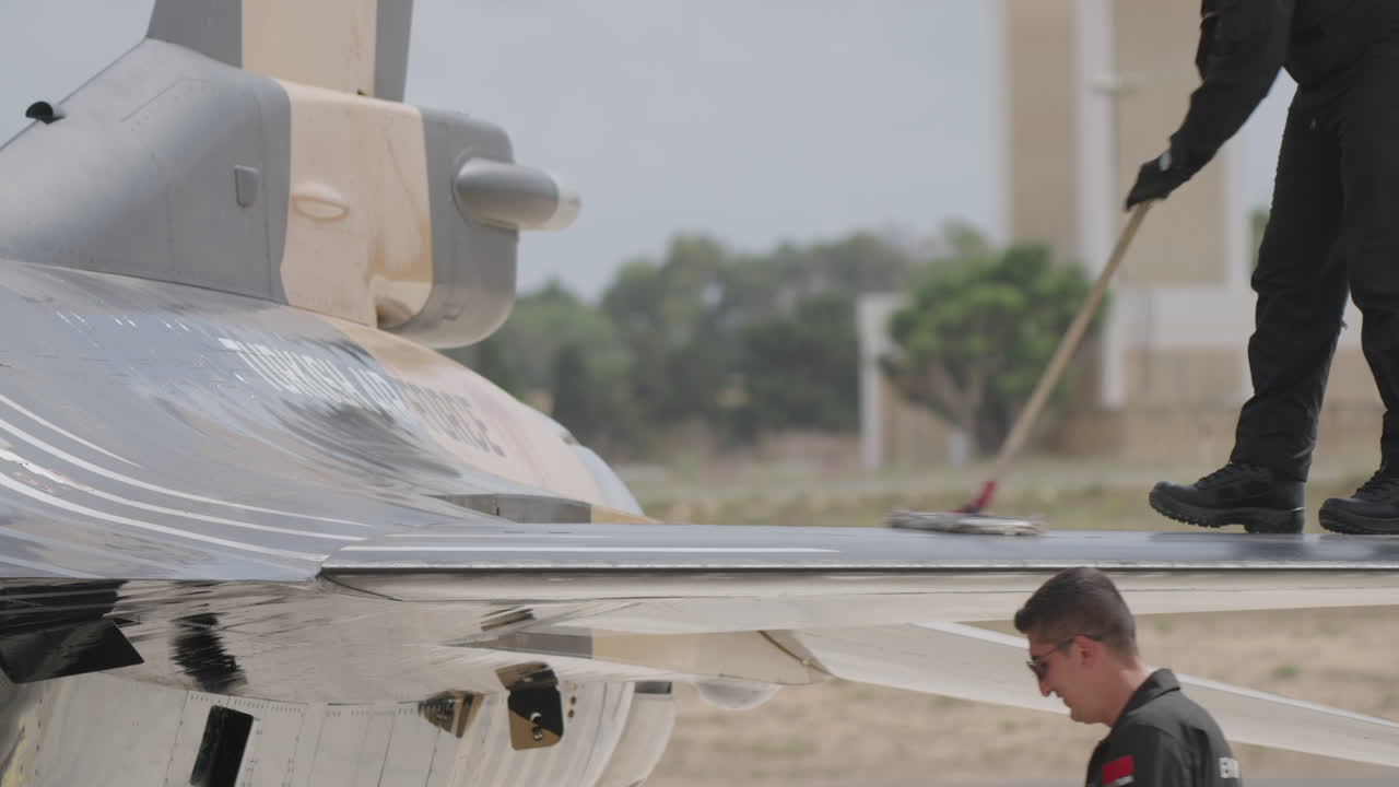 Personale di terra che pulisce e ispeziona un aereo militare sull'asfalto