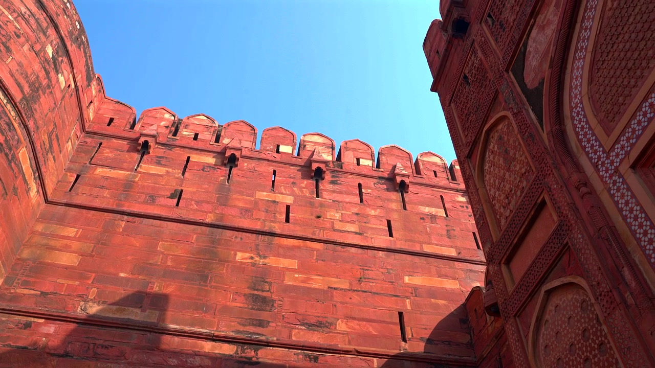 Bir UNESCO Dünya Mirası Alanı olan Agra Kalesi'nin karmaşık kırmızı kumtaşının yakın çekimi, cephe mozaiklerindeki detay seviyesini ve Babür mimarisinin ihtişamını gözler önüne seriyor.