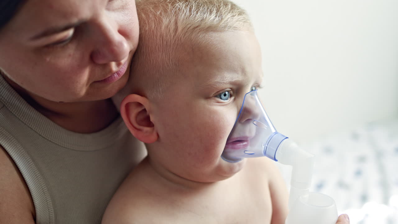Maman fait une inhalation à son petit garçon. Auto-traitement de l'enfant à domicile. Inhalation avec un masque sur le visage d'un jeune enfant. Traitement de la toux chez les enfants.
