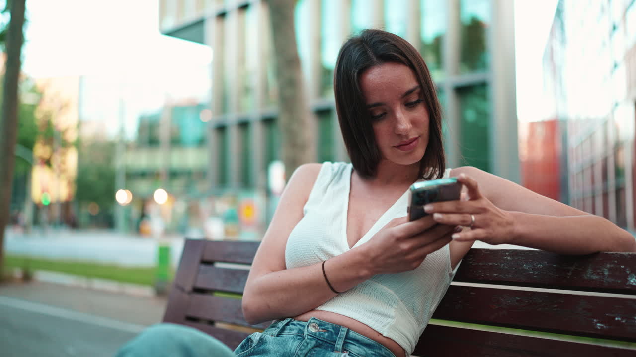 Woman using mobile phone while sitting on a bench