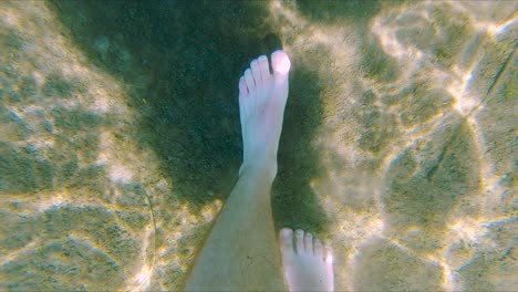 white male feet walk on sand bottom of lake, wide underwater close up