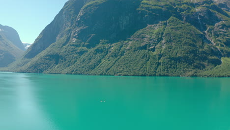 vista lejana de veleros en un lago prístino con exuberantes montañas forestales cerca de stryn, condado de vestland, noruega