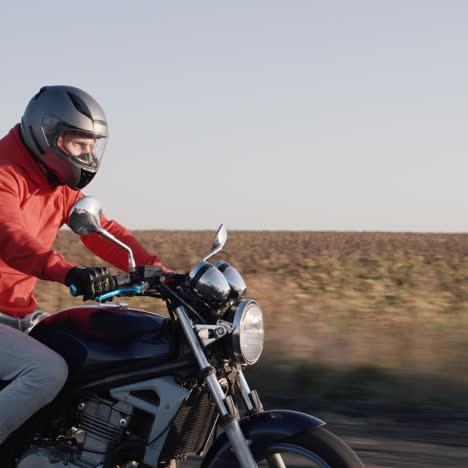 biker rides on a country road against a backdrop of fields