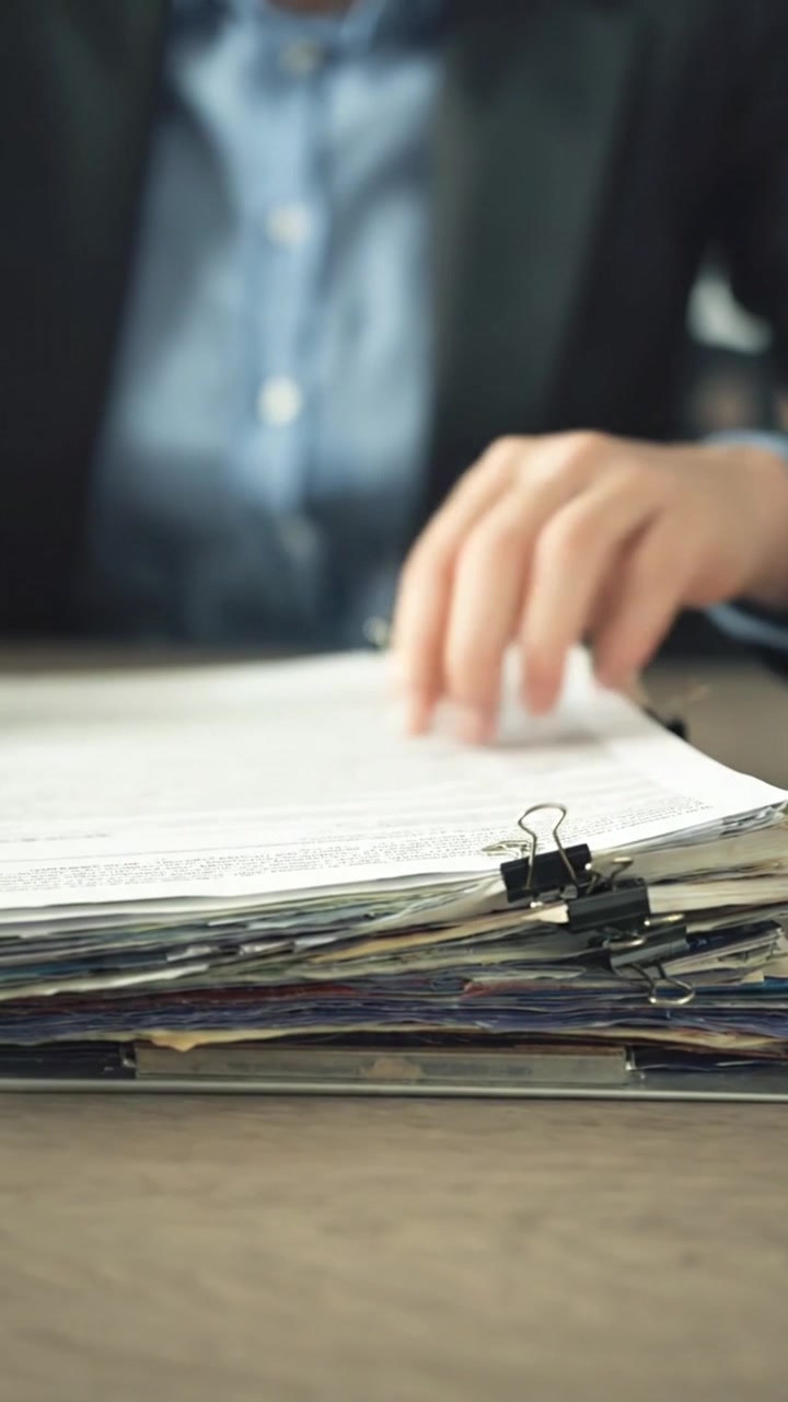 Manos de empresario buscando documentos en una pila de papeles