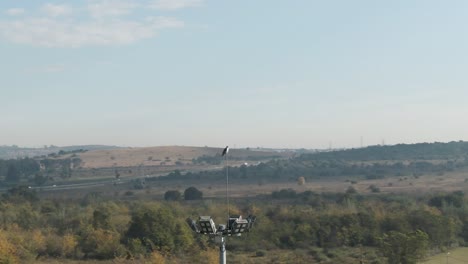 drone aerial orbit of a falcon bird on a flood light tower