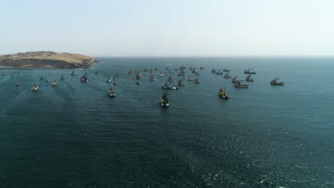 Aerial-view-approaching-fishing-ships-anchored-on-the-shore-of-sunny-Huacho,-Peru