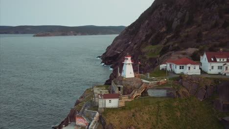 Faro-De-Fort-Amherst-Sobre-Un-Acantilado-Rocoso-Junto-Al-Mar-Con-Edificios-Blancos-Y-Tejados-Rojos