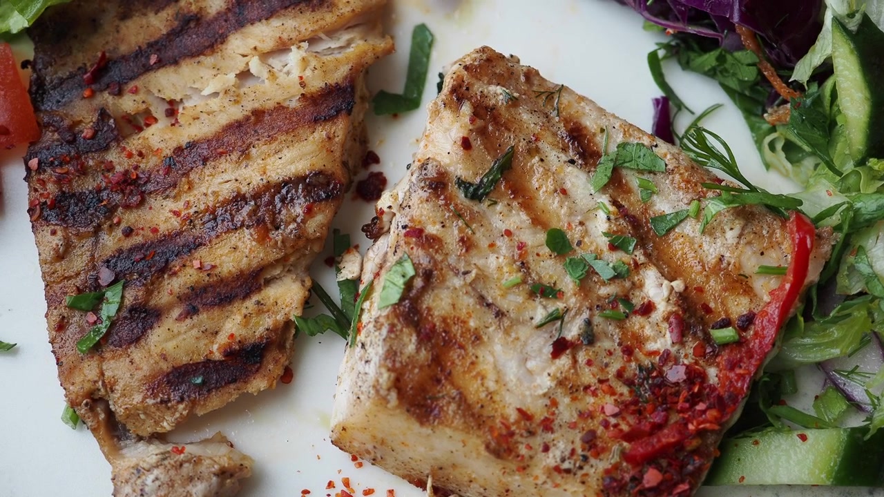 Filets de poisson grillés sains servis avec une salade de légumes frais