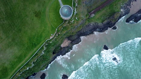 Downward-drone-shot-of-Mussenden-Temple-located-on-cliffs-near-Castlerock-in-County-Londonderry,-in-Northern-Ireland