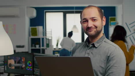 trabajador de edición de video de pie frente a la cámara sonriendo
