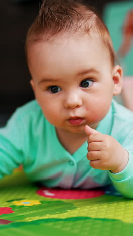 sweet baby boy with funny hair lies on a mat. adorable toddler interested with toys. close up. vertical video