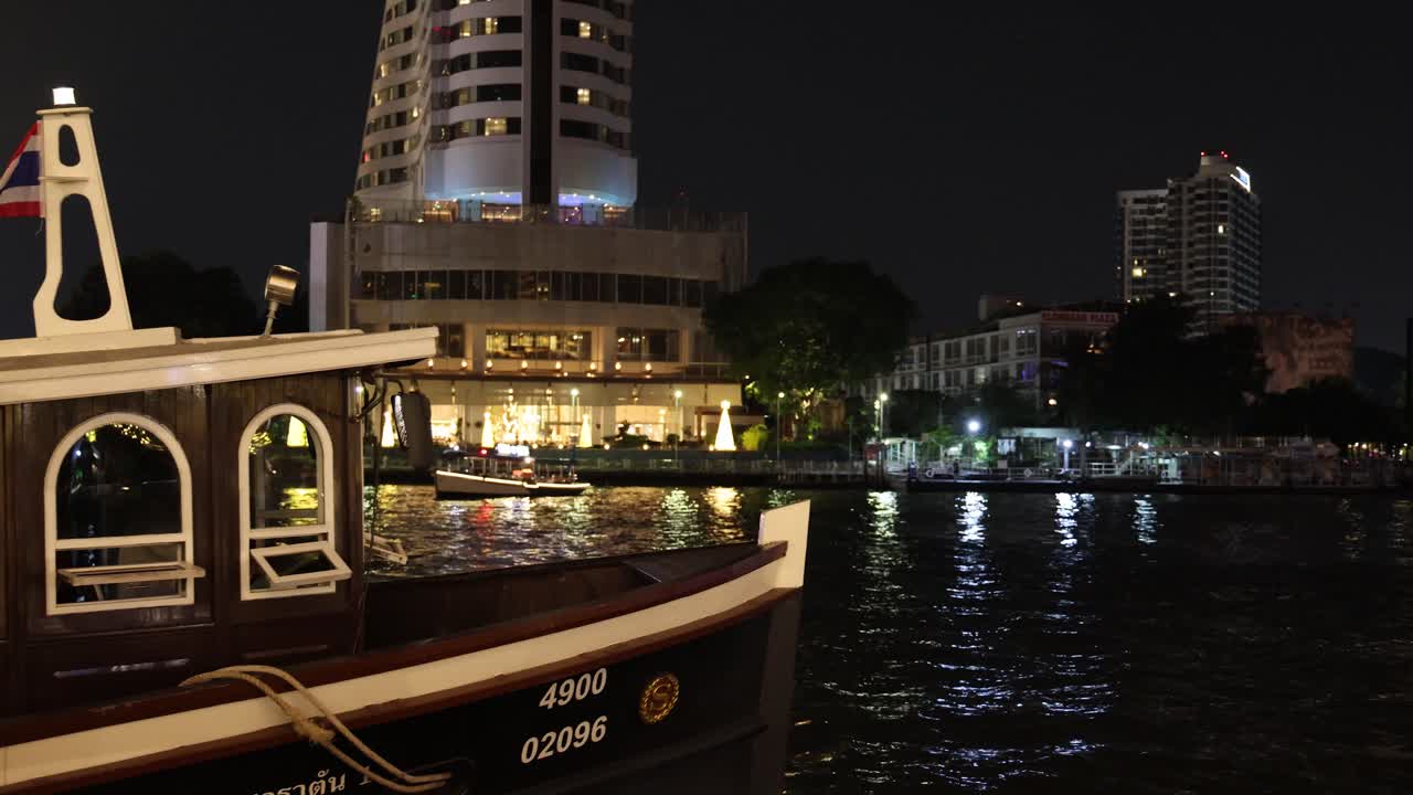 배 는 강 을 따라 조명 된 건물 을 지나간다