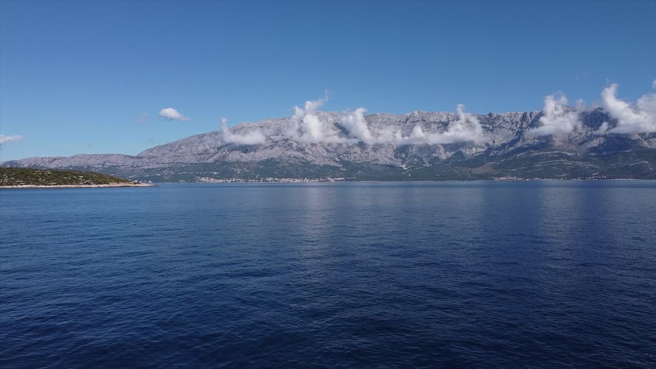 Drone rising up over open ocean with beautiful coast line with mountains and clouds in Croatia Europe