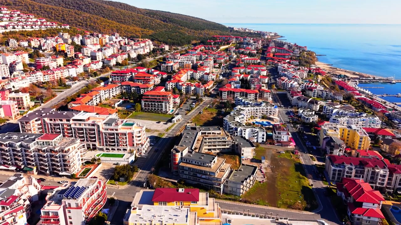 Kohotettu näkymä merenrantakaupunkiin vuorten rinteellä, Bulgaria. Punakattoisia rakennuksia ulottuen kohti tyyntä merta ja rantaa.