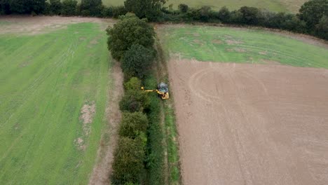 Aerial-View-Over-Tractor-Cutting-And-Maintaining-Hedge-In-Field