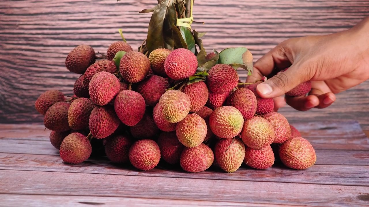 Tangan Memetik Buah Leci Segar dari Seikat