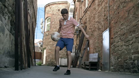 a young man keeping the soccer ball in the air and juggling on the street