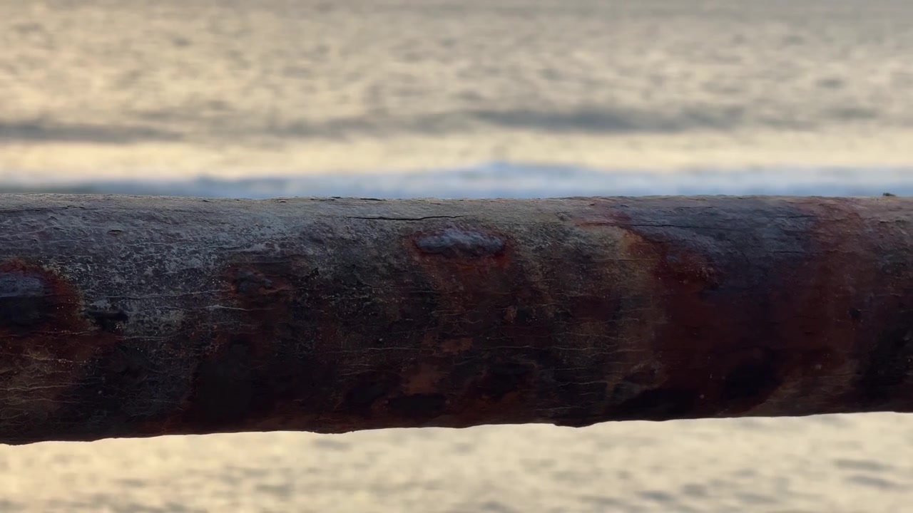 Rusty Metal Railing Overlooking Ocean Waves at Sunset