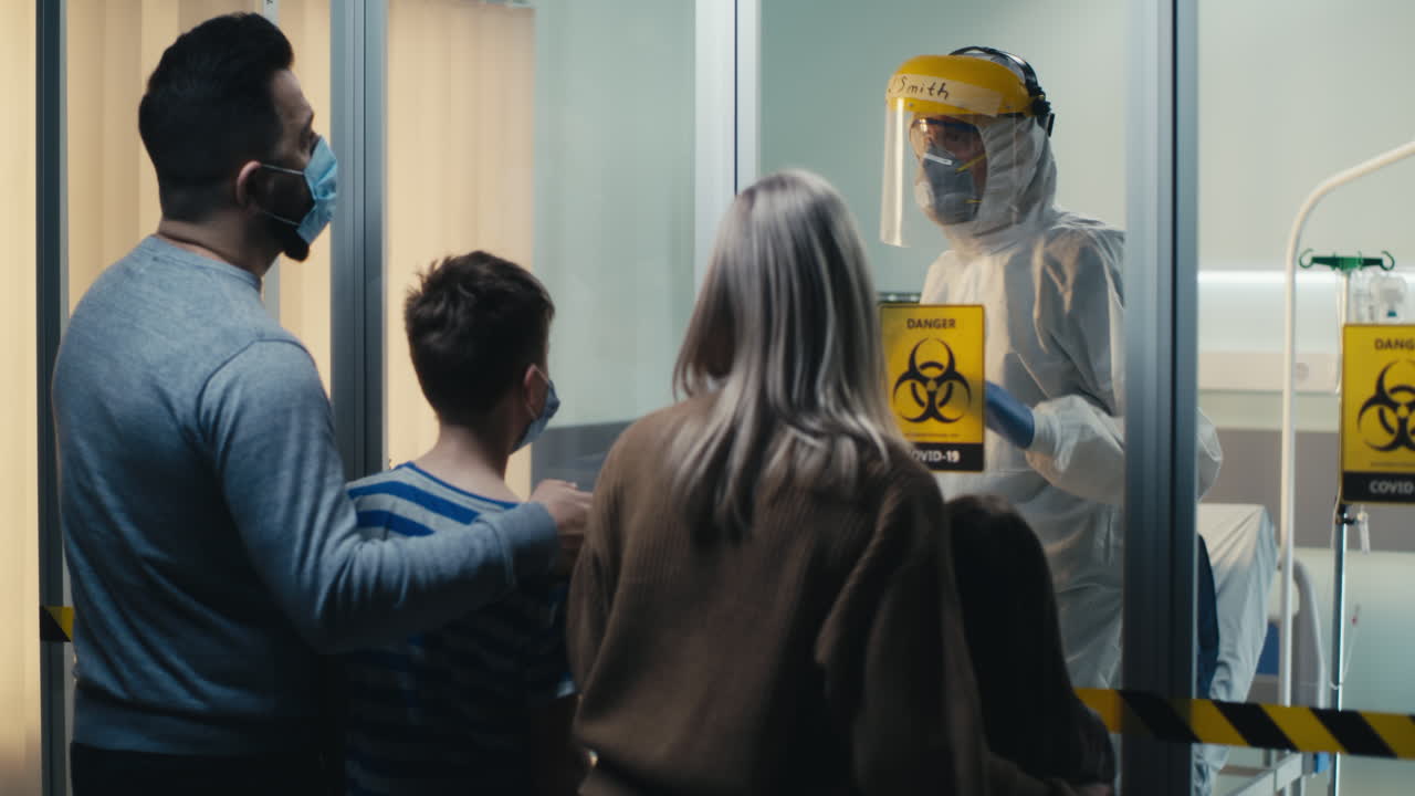 Family communicates with healthcare worker through glass in COVID-19 isolation ward