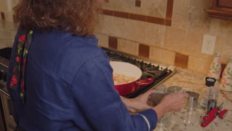 woman pouring can of chick peas in to hot sauce pan