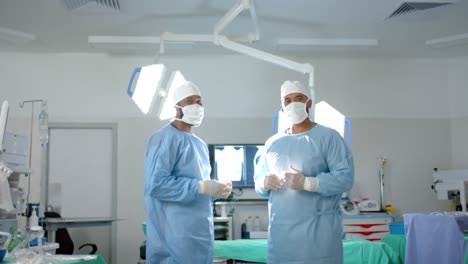 Portrait-of-diverse-male-surgeons-wearing-surgical-gowns-in-operating-theatre,-slow-motion