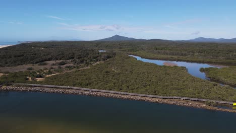 Vistas-Aéreas-Del-Paseo-Marítimo-De-Urunga-A-Lo-Largo-De-Las-Orillas-Del-Río-Kalang,-Hasta-El-Cruce-Con-El-Río-Bellinger-Y-Hacia-El-Océano