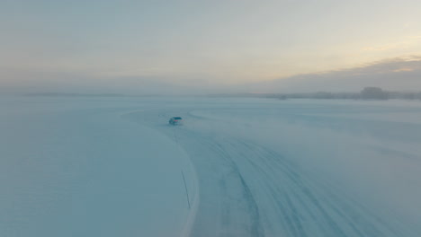 chasing speeding driver drifting corners on lapland ice lake aerial view at sunrise